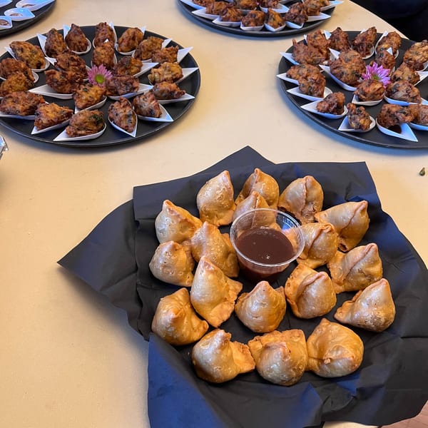 Platters of samosas and pakoras with dipping sauces, ready to be served at an event.